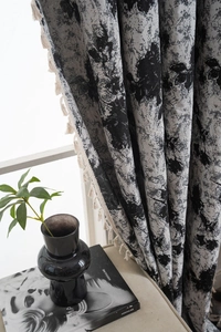 Detailed view of grey ink pattern fabric with decorative cream tassels for window curtains