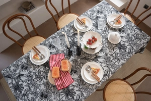 Detail of black and white floral forest pattern tablecloth with red checkered napkin