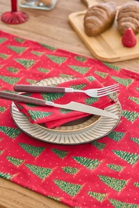 Detail of red Christmas cloth napkin with green leaf print on elegant ceramic plate