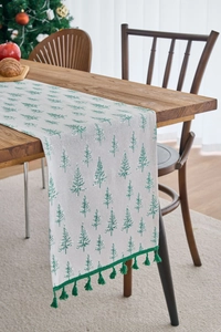 Close-up of Christmas table runner with green pine tree patterns and decorative tassels