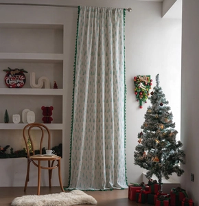 Detail of Christmas curtain featuring green pine tree patterns and decorative fringe tassels