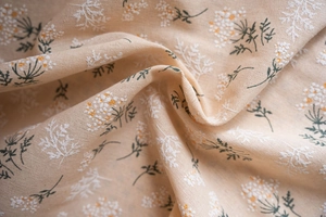 Detailed close-up of cream floral cotton linen fabric with natural texture and soft drape