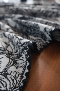 Macro shot of black and white Toile de Jouy floral jacquard fabric on wood table