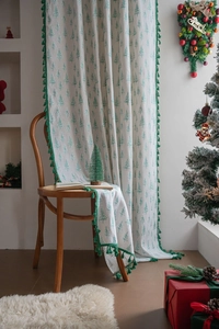 Detailed view of cream fabric featuring green pine tree prints and festive green tassel trim