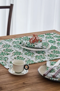 Dettaglio della stampa festiva di poinsettia verde su tessuto di tovagliolo in cotone bianco