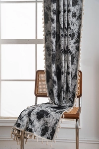 Detail of jacquard curtain with black floral pattern and cream tassel fringe on a chair