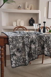 Close-up of black and white floral jacquard table runner with scalloped edges on wood table
