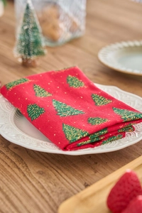 Detail of red Christmas cloth napkin with green tree print on a white plate
