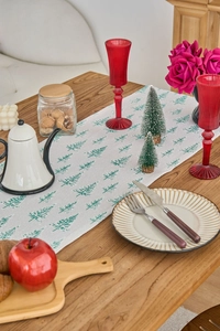 Detail of Christmas table runner with green pine tree patterns on textured fabric