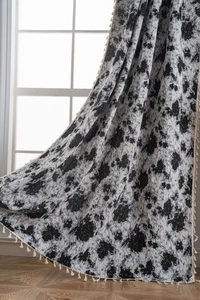 Close-up of vintage floral jacquard fabric with elegant cream fringe tassels on curtain