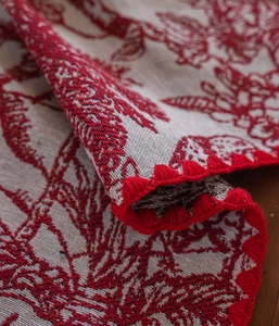 Close-up of vintage floral jacquard tablecloth with intricate red crochet edge detail