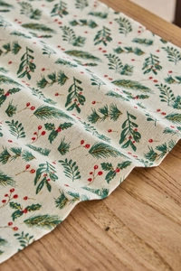 Macro detail of Christmas napkin featuring green pine leaves and golden glitter berries