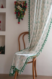 Detail of green pine tree pattern and green pom-pom fringe on white Christmas fabric curtain