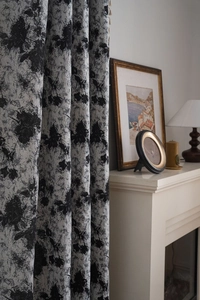 Detail of floral jacquard curtain with elegant fringe on a white fireplace backdrop