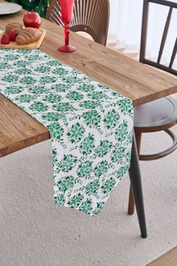 Detail of Christmas green and gold floral table runner on rustic wooden dining table