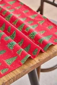 Close-up of festive red napkin with green Christmas tree print on wooden table