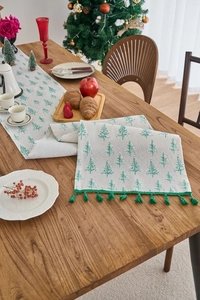 Close-up of Christmas table runner with green tree jacquard and emerald fringe tassels
