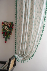 Detail of cream linen curtain featuring green pine tree print and tassel fringe edges