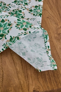 Dettaglio tovagliolo bianco con stampe floreali verdi e dorate e cuciture a orlo rifinite