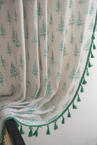 Detail of linen curtain with green pine print and decorative fringe trim on the edge