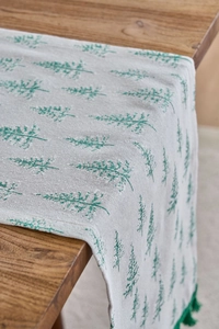 Detail of green pine tree pattern and fringe tassels on a knit Christmas table runner