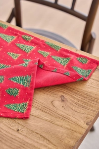 Detail of red Christmas table runner with green and gold glitter tree patterns