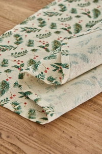 Detailed macro view of Christmas table napkin with green pine and red berry patterns