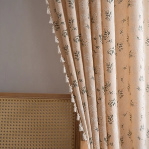 Floral print cream curtain with white tassel fringe in a cozy home interior setting