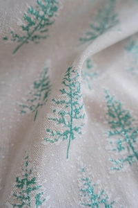 Macro detail of beige linen fabric with green glitter Christmas tree and white snowflakes