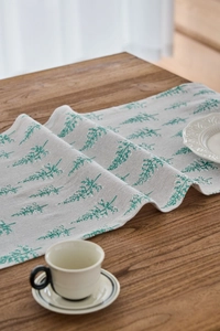 Close-up of green cedar tree print on linen table runner atop dark wood surface