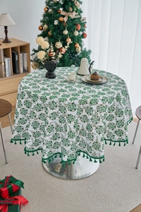 Close-up of pine branch print on round tablecloth with elegant green tassel trim detail