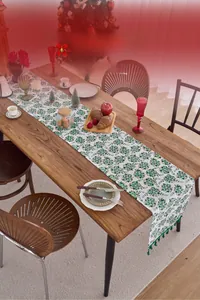Detail of Christmas table runner with green holly prints and golden foil with tassels