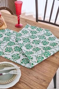 Detail of Christmas green table runner with gold floral patterns on a wooden table