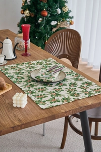 Detail view of linen Christmas napkins with green holly leaves and red berry print pattern