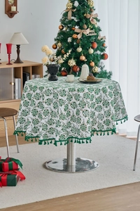 Detail of round Christmas tablecloth with pine needle print and green tassel fringe trim