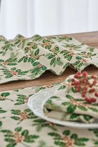 Detailed view of Christmas cloth napkin with green holly leaves and red berry print