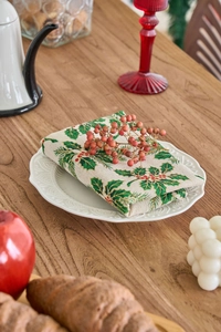 Close-up of festive cotton linen napkins with green holly and red berry patterns