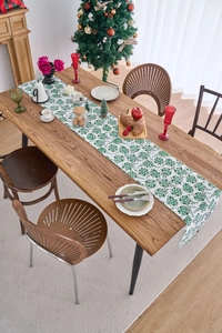 Detail of white table runner with green floral patterns for Christmas dining setting