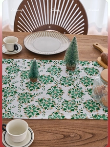 Detailed Christmas table runner with green poinsettia prints and gold foil leaf patterns