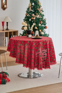 Detail of red Christmas tablecloth with pine tree prints and pom pom fringe edges