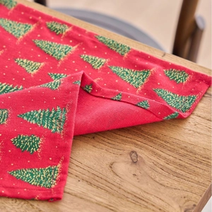 Christmas table runner with green tree prints on red fabric over a wooden background