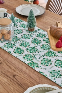 Detailed macro view of festive green and gold Christmas flower pattern on a table runner