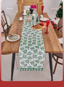 Detailed view of green Christmas snowflake table runner with fringe on a wooden table