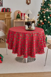 Detail of red round Christmas tablecloth with pine tree prints and pompom fringe