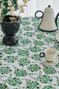 Detail of Christmas tablecloth with green pine and gold snowflake print on white fabric