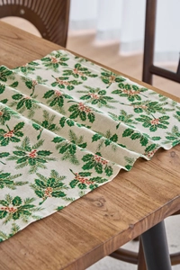 Detail of Christmas napkin fabric featuring green holly leaves and red berries on linen