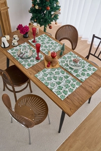 Detail view of four Christmas placemats with green leaves and gold festive patterns