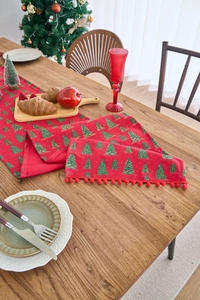 Detail of red Christmas table runner with green gold foil trees and red pom-pom trim