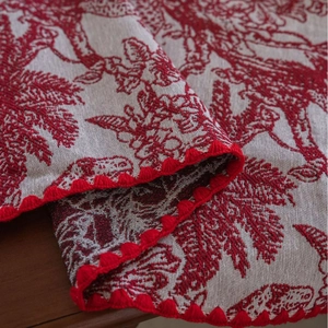 Red Toile de Jouy tablecloth with elegant floral patterns and crochet pom pom edges