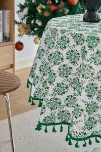 Detailed view of white Christmas tablecloth featuring green pine needles and fringe tassels